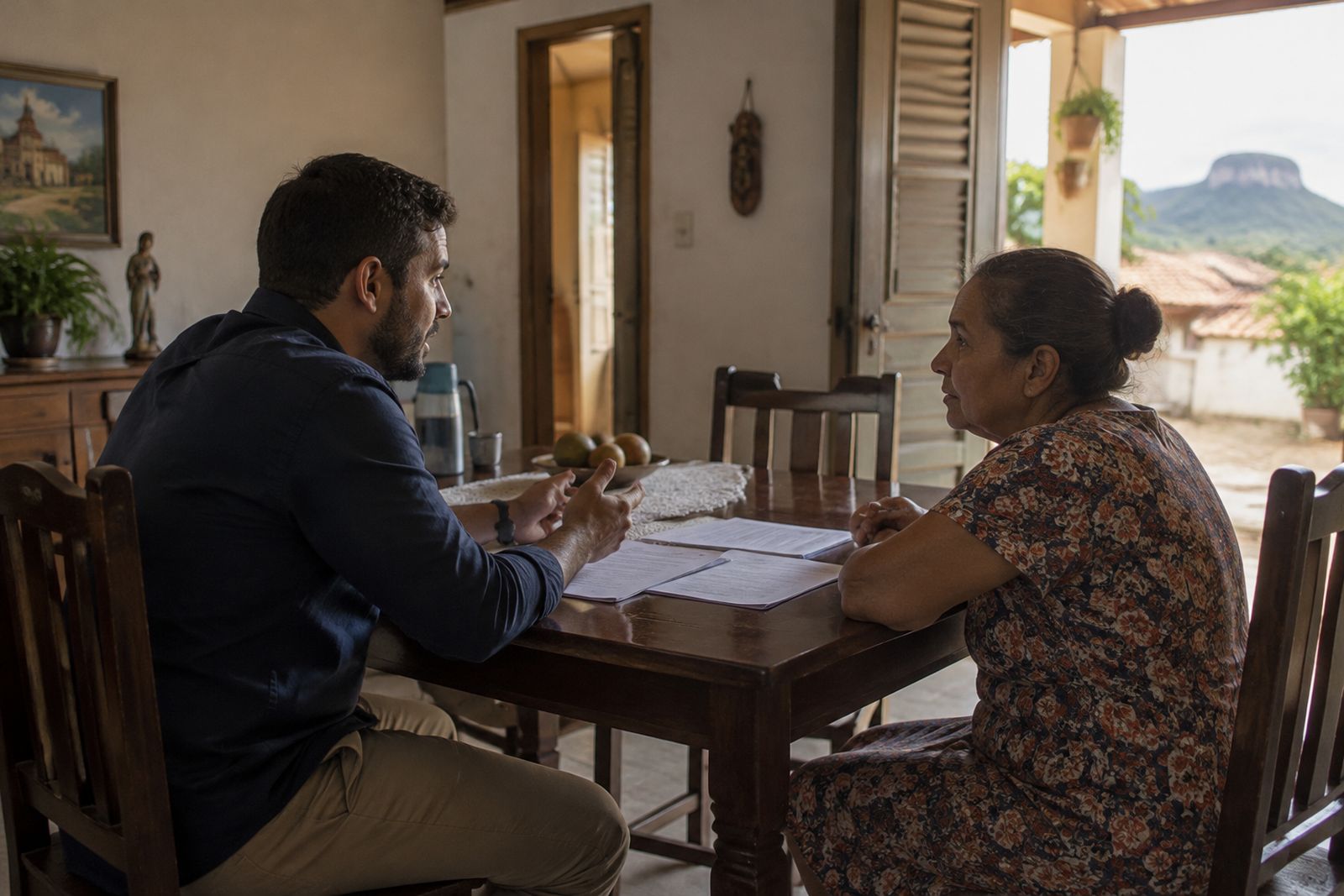 Comprador e proprietária conversam à mesa sobre o encerramento de uma compra de imóvel.
